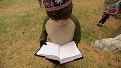 A young student prays with his sidur outside